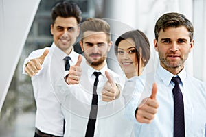 Successful young business people showing thumbs up
