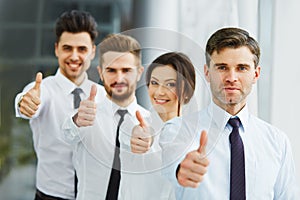 Successful young business people showing thumbs up