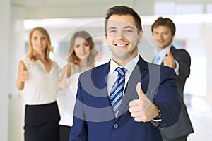 Successful young business people showing thumbs up sign