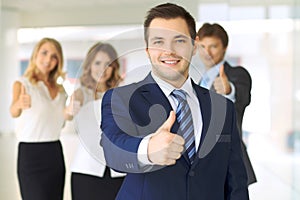 Successful young business people showing thumbs up sign