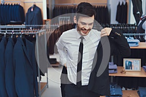 Successful young businessman measures jacket in business mens clothing store.