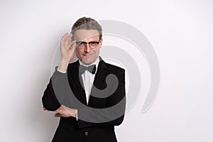 Successful young businessman proud of himself, fixing or touching his eye glasses. Half-length front portrait of a