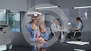 Successful young businesswoman in virtual reality headset working in modern office