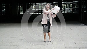 Successful Young Caucasian Business Woman Raising Her Arms With Document Folder at Urban Building Background. Happy