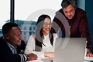 Successful young diverse group of businesspeople working together on a laptop in modern office