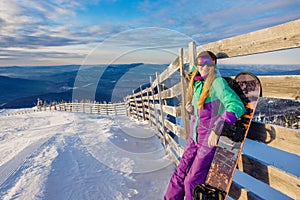 Successful young girl snowboarding in the mountains Sheregesh. Snowboarder resting. Stylish caucasian snowboarder. Snowboarder