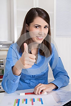 Successful young happy business woman sitting in her office.