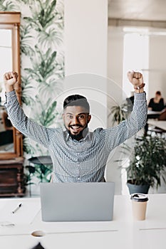 Successful young indian businessman enjoying success at his desk