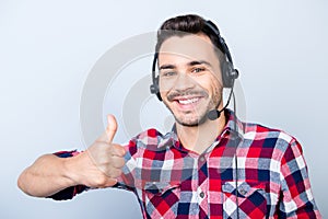 Successful young man operator of a telemarketing is smiling, wearing a headset. He is isolated on a pure light