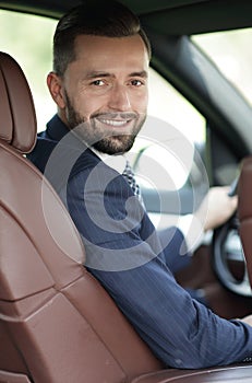 Handsome young man sitting in the front seat of a car looking at the camera