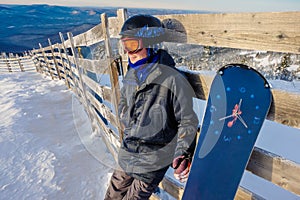 Successful young man snowboarding in the mountains Sheregesh. Snowboarder resting on mountain top. Caucasian snowboarder on a