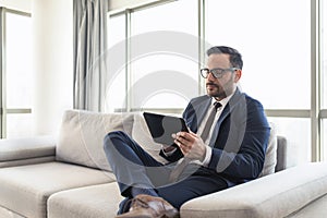 Successful young manager sitting on a sofa reading news