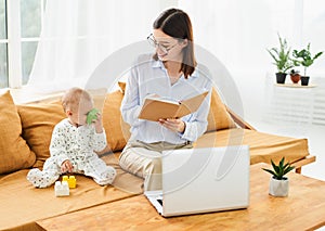 Successful young mother with newborn baby working in online conference mode