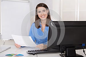 Successful young smiling business woman sitting in her office.