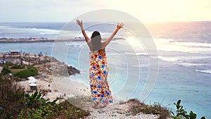Successful young woman reached top of moutain. Girl rise her hands in the air. Top view on beautiful ocean between rocks