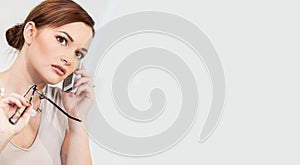 Successful Young Woman Talking on her Mobile Cell Phone Holding Glasses