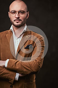 Successfull bald businessman posing in a studio wearing stylish velvet jacket, white shirt and glasses