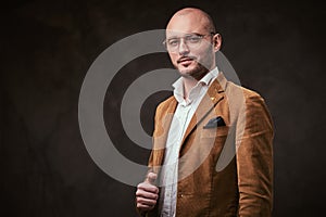 Successfull bald businessman posing in a studio wearing stylish velvet jacket, white shirt and glasses