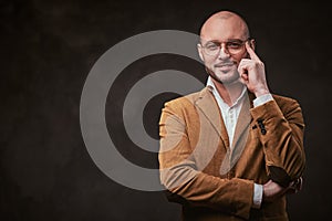 Successfull bald businessman posing in a studio wearing stylish velvet jacket, white shirt and glasses