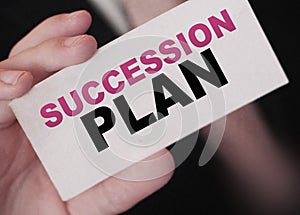 Succession Plan words on a card in hand of businessman. Business profit and success concept