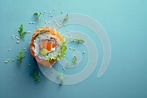 Succulent, bright and vibrant salmon sushi roll, with sushi rice and rocket salad on a light blue background with space for copy
