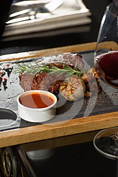 Succulent grilled beef steak with red wine, seasonings, fresh rosemary and grilled vegetables on cutting board