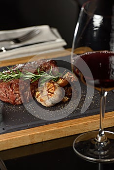 Succulent grilled beef steak with red wine, seasonings, fresh rosemary and grilled vegetables on cutting board