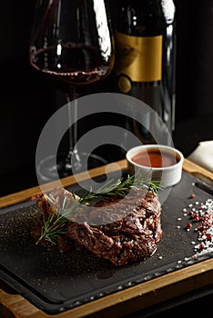 Succulent grilled beef steak with red wine, seasonings, fresh rosemary and grilled vegetables on cutting board