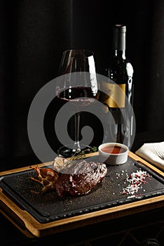 Succulent grilled beef steak with red wine, seasonings, fresh rosemary and grilled vegetables on cutting board