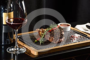 Succulent grilled beef steak with red wine, seasonings, fresh rosemary and grilled vegetables on cutting board