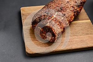 Succulent thick juicy grilled fillet steak served on an old wooden board over black background