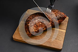 Succulent thick juicy grilled fillet steak served on an old wooden board over black background