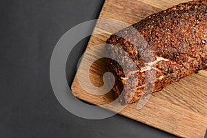 Succulent thick juicy grilled fillet steak served on an old wooden board over black background