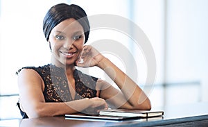 Sucessful black businesswoman looking into camera while seated at counter
