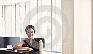 Sucessful black businesswoman looking into camera while seated at counter