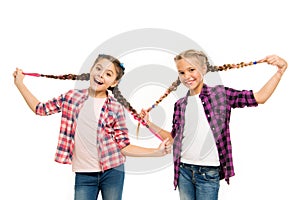 Such a long hair. Happy little girls wear plaited hair. Cute small childred hold hair braids. Luxurious hair extensions