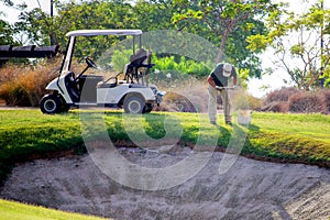 Sucina, Spain - August 08 2018: A groundsman on a golf course, taking soil samples from the fairway near a bunker with an augur.