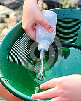 Suctioning gold particles from a pan with a snuffer bottle