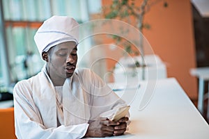 Sudanese business man in traditional outfit using mobile phone in office photo
