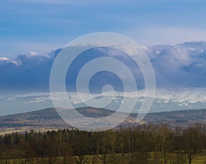 The Sudetes seen from a distance with the peaks partially covered with a layer of dense clouds.