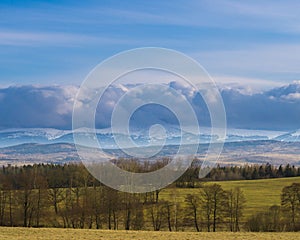 The Sudetes seen from a distance with the peaks partially covered with a layer of dense clouds.