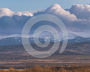 The Sudetes seen from a distance with the peaks partially covered with a layer of dense clouds.