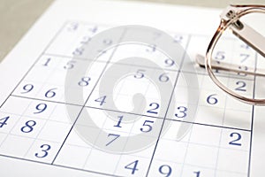 Sudoku and eyeglasses on table, closeup view