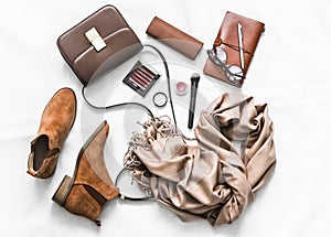 Suede shoes, cashmere scarf, bag, cosmetics, organizer on a light background, top view. Fashion concept