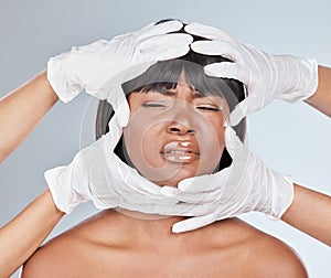 Suffer for beauty, they said. Studio shot of an attractive young woman getting her face analysed by gloved hands and