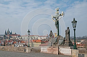 Suffering Christ. Statue on Charles bridge in Prague. Prague castle on backgraund
