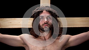Suffering crucified messiah looking camera on black background, religious faith