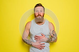 Suffering man with beard and tattoos has stomach ache