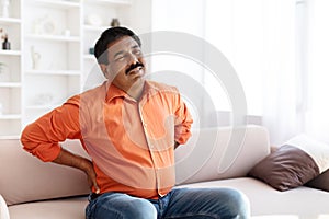 Suffering middle aged indian man feeling lower back pain