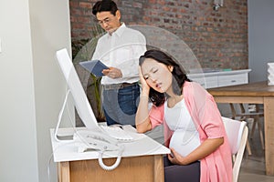 Suffering pregnant woman sitting at desk